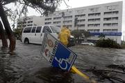 People try to cross a flooded street in the resort city of Cancun, Mexico, after the passing of Hurricane Wilma on Saturday. Wilma punished Mexico's Caribbean coastline for a second day, ripping away storefronts, peeling back roofs and forcing tourists and residents trapped in hotels and shelters to scramble to higher floors.