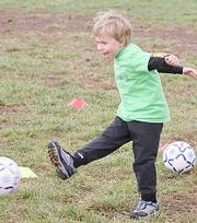 Joey Bassett smiles as he kicks the ball towards the net during warm-ups on Saturday at Youth Sports Inc.