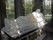 A marble statue of Henry Shaw rests above his tomb in the mausoleum outside Tower Grove House. He clasps a single rose in his right hand.