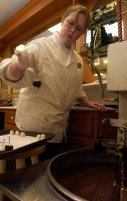 Alison Vavra, an employee of Riverfront Chocolates, prepares double-dipped cherries in different types of chocolate Thursday afternoon at the shop, 1 Riverfront Plaza. Riverfront Chocolates owner Cheryl Wetherington says dark chocolate makes up about 25 percent of her shop's sales.