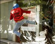 A protester kicks in a window of a bank Friday during a march against the presence of President Bush in the Fourth Summit of the Americas in the Atlantic resort city of Mar del Plata, Argentina.
