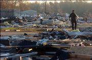 A police officer surveys at sunrise the damage at the Eastbrook Mobile Home Park at sunrise Sunday in Evansville, Ind. A tornado ripped across southwestern Indiana and northern Kentucky early Sunday, killing at least 22 people, state and county authorities said.