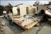 Mary Heck walks by part of Sherri Hudson's house Monday after it was damage by a tornado in Newburgh, Ind. The tornado ripped across southwestern Indiana and northern Kentucky, killing at least 22 people, wrecking homes and knocking out power to thousands.