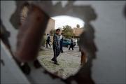An Iraqi boy is framed by a damaged door Monday after a mortar shell explosion occurred in the area, in Baghdad, Iraq. Five people were killed in east Baghdad when a mortar shell exploded near a Turkomen club, police said. It was unclear if the club was the target. Four people were injured.