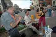 From left, musicians Dan Kozak, Carlos Martinez and John Anderson perform together for the first time as a band at the corner of Seventh and Massachusetts streets. The musicians recently connected with one another on the streets of Lawrence and will perform tonight at the Ecumenical Christian Ministries building at KU.