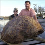 Allen Binford, left, poses with Steve Arnold, and the 1,400-pound meteorite that was discovered on Binford's farm. Arnold, a professional meteorite hunter from Kingson, Ark., found the rock underground two weeks ago in Kiowa County's Brenham Township.