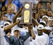 North Carolina coach Roy Williams holds the trophy with his team after the Tar Heels beat Illinois, 75-70, in the NCAA championship game. Williams, shown April 4 in St. Louis, and the now-unranked Tar Heels lost four underclassmen to the NBA and their top seven scorers from last season, leaving behind a short bench and a freshman-heavy rotation.