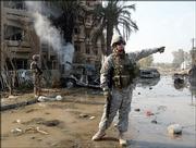 A U.S. soldier, right, secures the area where two car bombs detonated Friday in a central Baghdad, Iraq, residential neighborhood, killing at least six people and injuring 43 more between an Interior Ministry building and a hotel occupied by foreign journalists.