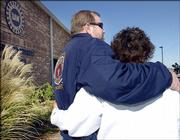 Tim O'Connor, left, president of Central Oklahoma Labor Federation, hugs UAW Local 1999 financial secretary Judy Calhoun, as they listen to a General Motors news conference at the UAW Local headquarters in Oklahoma City. GM's Oklahoma City Assembly plant is slated for closure early next year.