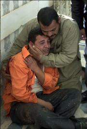 A man is consoled by a relative as he mourns the death of his family members Monday inside Baqouba hospital, Iraq. U.S. forces mistakenly fired on a civilian vehicle outside of an American military base north of Baghdad on Monday, killing at least three people, including one child, a U.S. spokesman said. Iraqi police said four people were killed. The reason for the discrepancy was unclear.