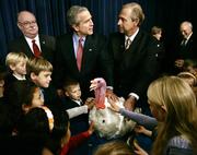 President Bush invites local schoolchildren to pet Marshmallow, the beneficiary of this Thanksgiving's traditional presidential pardon, Tuesday in Washington. Turkey farmer James Trites, right, steadies Marshmallow. National Turkey Federation Chairman Pete Rothfork watches at left.