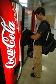 Free State High School senior Nathan Desetti makes a purchase Tuesday at one of the Coke machines at the high school. Concessions will be made by the vending companies to offer healthier drinks, although Lawrence schools already have options other than soda.