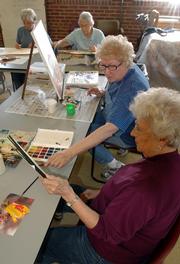 At the Tuesday Painters gathering at the Douglas County Senior Center, Charlotte Neese, Eudora, foreground left, and Joyce Witulski, Lawrence, foreground right, review a painting of Witulski's. With the city considering building a new library or expanding the current one, some folks are concerned about the future of the senior center located just to the south.