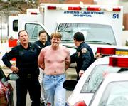 Farron Barksdale smiles as he is taken to a squad car in Athens, Ala., in this 2004 file photo after he allegedly gunned down two Athens police officers. People with a history of mental illness are banned by federal law from purchasing guns.