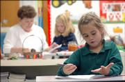 Delaeny Shelton, foreground right, works on a math exercise Monday in her first-grade class at Veritas Christian School. In the background, first-grade teacher Elaine Lackrone assists a student. Education Commissioner Bob Corkins' transition chief, Daniel Harden, says parents should be able to send their children within the public school system to schools like Veritas Christian in Lawrence or Cair Paravel-Latin in Topeka. It's about giving parents more choices, he said.