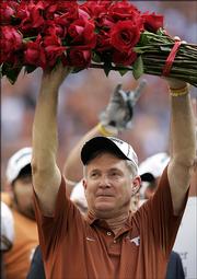 Texas coach Mack Brown holds a bundle of roses after beating Colorado, 70-3, to win the Big 12 title. The Longhorns clinched a berth in the Rose Bowl with the victory Saturday in Houston. Next up for UT? Top-ranked USC, which hammered UCLA, 66-19.
