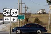 A motorist stops at the intersection of U.S. Highways 59 and 56 just west of Baldwin Tuesday afternoon. The home in the background sits on beams ready to move to a new location because of planned road construction.