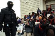 A Capitol Police officer looks over a group of protesters kneeling on the steps of the Cannon House Office Building in Washington. Religious-based activists protested proposed Republican cuts to Medicaid and other programs for the poor on Wednesday; 115 of the protesters were arrested.