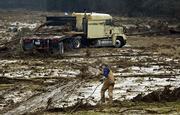 Tow truck driver Kerry Buckley drags a cable out to a truck that was washed off a highway after a billion-gallon torrent of water was released from a reservoir after its retaining wall was breached Wednesday in Lestervile, Mo.