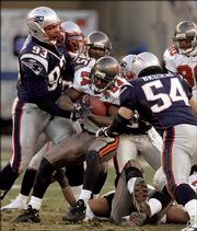 Tampa Bay's Carnell Williams (24) gets gang-tackled by New England's Richard Seymour (93), Rosevelt Colvin (59) and Tedy Bruschi (54) during the third quarter of the Patriots' 28-0 victory. New England won Saturday in Foxborough, Mass.