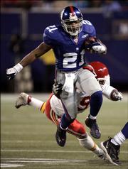 New York Giants running back Tiki bBarber (21) escapes the attempted tackle of Kansas City linebacker Kendrell Bell during the third quarter. Barber racked up 220 rushing yards, helping the Giants deliver the Chiefs another blow to their playoff hopes, 27-17, Saturday in East Rutherford, N.J.