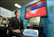 Stephen Agritelley, director of Intel's Health Systems Research Lab, demonstrates a medication prompting system during the White House Conference on Aging Dec. 11 in Washington. The medication prompting system helps seniors remember to take their medication with reminders on a television screen, or on a wrist watch.