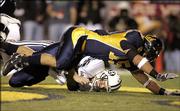 California's Anthony Felder, top, falls over Brigham Young quarterback John Beck in the second quarter of the Pioneer Purevision Las Vegas Bowl. Cal won, 35-28, Thursday in Vegas.