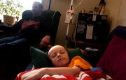 Hooked up to his feeding tube, 5-year-old Christian Faulkner rests in his Lawrence home Saturday afternoon with his father, Jay Faulkner. Christian spent the previous two weeks at Children's Mercy Hospital in Kansas City, Mo., successfully undergoing treatment for removal of a cancerous tumor that was across his lungs.