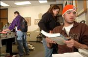 Lorenzo Funmaker, an Oneida, Wis., freshman at Haskell Indian Nations University, foreground right, picks up his textbooks at the campus library. Funmaker visited the library Thursday, a day after classes started at Haskell. The university is feeling the effects of budget cuts from the federal government, and may have to furlough some employees to make ends meet.
