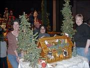 Social Security Administration employees, from left, Linda McCoy, Gloria Asher and Connie Meyer work on the office's entry for the Festival of Trees auction. Their country log cabin sold for $500 during the Festival of Trees auction Nov. 29 at Liberty Hall. Proceeds from the auction went to The Shelter Inc.
