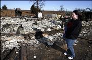 Janette Anderson, of Ardmore, Okla., holds her 3-year old son, Hawk, on Friday as she looks over what remains of the house belonging to her father- and mother-in-law, Larry and Tammy Anderson, near Fox, Okla. The house was destroyed Thursday by a grass fire.