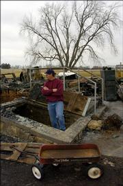 Rob Harris looks over the remains of the Breithaupt family's burned-out home southwest of Lawrence. Harris, a neighbor, is helping collect donations for the family.
