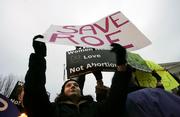 Trish Calamari, 28, raises her sign to block the signs of anti-abortion protesters who tried to disrupt a pro-choice candlelight vigil in front of the Supreme Court in Washington. Sunday was the 33rd anniversary of the Roe v. Wade decision that made abortion legal.