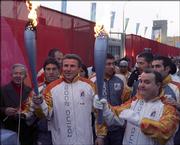 Ukrainian pole vault legend and ioc member sergie bubka, left center, carries an Olympic torch after passing the flame over to an unidentified torch bearer, right. Bubka toured the Winter Olympics athletes village in Turin, Itlay, with the flame on Thursday.