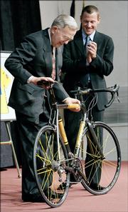 James Stowers Jr., left, American Century Investments founder, receives a bicycle from Lance Armstrong, seven-time Tour de France winner, Thursday at American Century's headquarters in Kansas City, Mo. The bicycle is a replica of one that Armstrong used for racing.