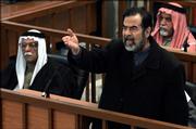Former Iraqi president Saddam Hussein gestures in court inside the heavily fortified Green Zone in Baghdad, Iraq as the latest session of his trial began Monday, Feb. 13, 2006. Saddam Hussein was forced to attend the latest session of his trial Monday, looking haggard and wearing a robe rather than his usual crisp suit as he shouted, "Down with Bush." Saddam and his seven co-defendants had vowed not to attend the trial until the return of their lawyers. The defense team are boycotting the proceedings until chief judge Raouf Abdel-Rahman is removed, alleging he is biased against their clients.
