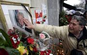 A supporter of former Serbian leader Slobodan Milosevic touches Milosevic's photograph Sunday in front of the Socialist Party of Serbia's headquarters in downtown Belgrade. Preliminary autopsy results show Milosevic died of a heart attack Saturday while awaiting trial at The Hague, Netherlands.