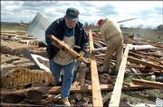 Don Troughton, of Overland Park, and Bruce Evans, of Lawrence, help clean up sheds at Pendleton's Country Market, 1446 E. 1850 Road, that were damaged in Sunday's storm.