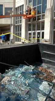 Kansas University Facility Operations personnel work to replace the windows at Budig Hall/Hoch Auditoria. The shards of many windows shattered during Sunday's storm were piled in the back of a truck Tuesday.