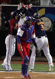 Japan's Toshiaki Imae, left, congratulates Nobuhiko Matsunaka, right, as Cuba's Ariel Pestano walks away after Matsunaka scored on a sacrifice fly in the sixth inning. Japan won the World Baseball Classic championship game, 10-6, Monday in San Diego.