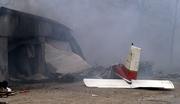 The tail section from the wreckage of a small plane that crashed lies near a storage unit that was engulfed in flames in Branson, Mo. The plane crashed about 12:30 p.m. Monday near a busy street, killing all four people aboard. Federal aviation investigators will begin examining the wreckage today.