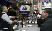 A barman and a Patron watch television to get election results in the eastern Ukrainian city of Donetsk. Exit polls Sunday showed Viktor Yanukovych's pro-Russian party taking the largest chunk of votes in a stunning comeback over Viktor Yushchenko, shown on the television, who took power in 2004's Orange Revolution.
