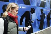 Hedwig Pagmar Hansson, a tourist from Stockholm, Sweden, listens to an Apple Video iPod as she walks next to an iPod advertisement Wednesday in downtown San Francisco. Owners of recent iPods will now be able to set how loud their digital music players can go. Apple Computer Inc. is making the setting available as part of a new software update. People concerned about hearing loss have welcomed the change.