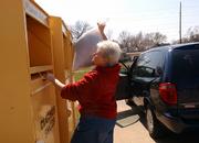 Lawrence resident Catherine Bolton drops off a bag of clothes into one of three Planet Aid boxes Saturday near 19th and Massachusetts streets.