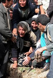 A woman who lost relatives in Friday's earthquake mourns at their graves while others comfort her Saturday at the devastated village of Khalegh Ali, Iran. Fearing new temblors, survivors of three strong earthquakes spent a cold night outdoors as officials wrapped up rescue operations after pulling out 70 bodies from under the rubble and rescuing 1,200 others.
