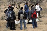 Carrying their belongings and gallons of water, people wait for darkness near the town of Sasabe, Mexico, before trying to cross illegally into the United States through the Arizona desert. Growing security along the border has made smuggling migrants a lucrative business.