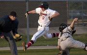 Lawrence Lions Marc Albers leaps past the Shawnee Mission West catcher to score at home plate during a
game Thursday at Holcom Park. Albers was the go-ahead run for the Lions in the 5th inning.