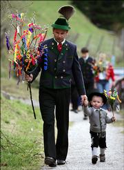 Dressed in traditional Bavarian highland attire, a German boy and his father carry their bouquets of decorated catkins in Ramsau, southern Germany. They were taking the bouquets to church for consecration, following an old tradition on Palm Sunday.