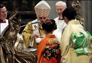 Pope Benedict XVI, center, baptizes a Japanese faithful during the Easter Vigil ceremony in Saint Peter's Basilica at the Vatican, Saturday, April 15, 2006.