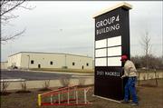 In East Lawrence, Bob Norris, of Huxtable and Associates, works on a sign at the company's new building, which used to be the Davol Plant.